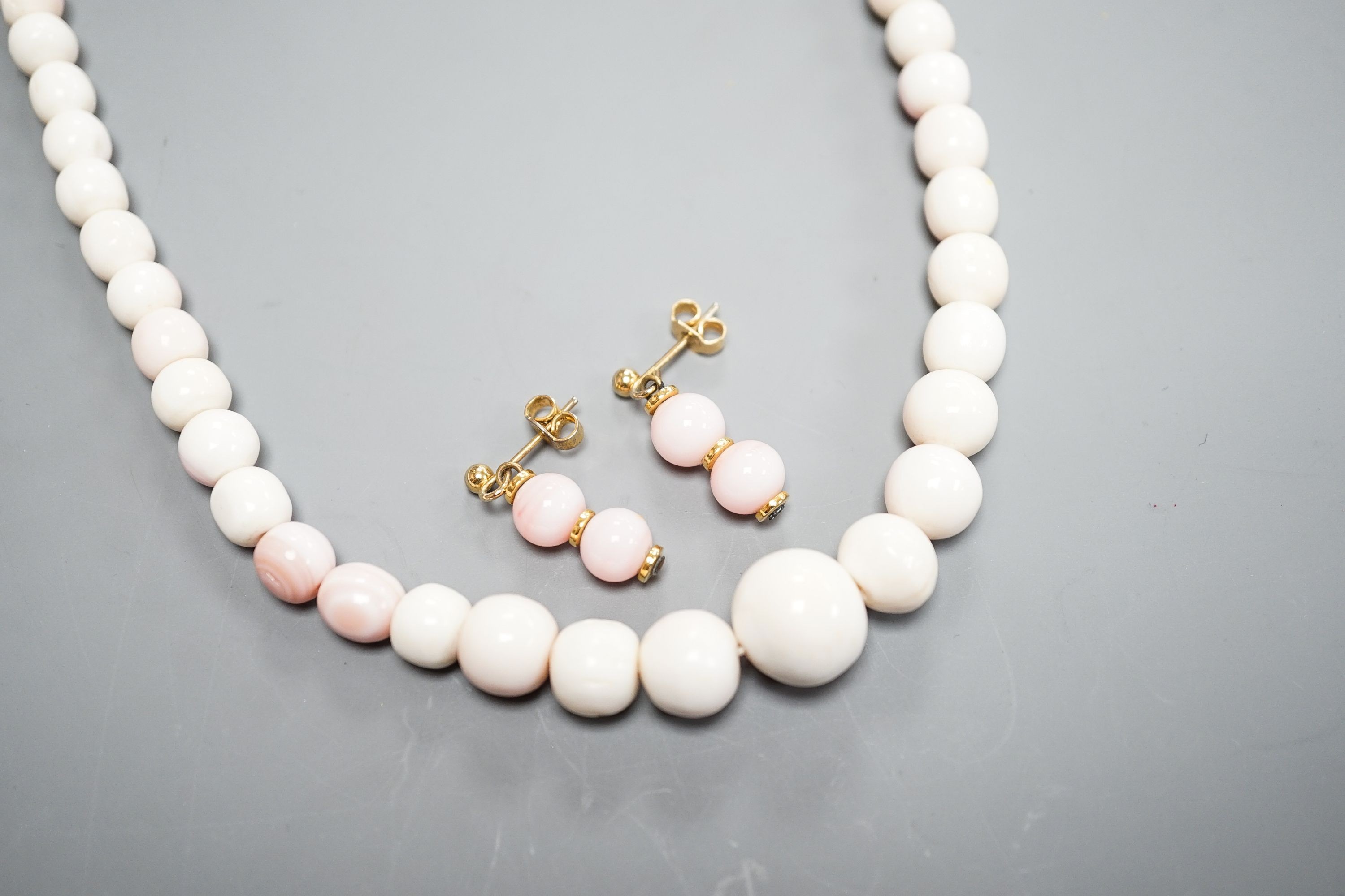 A single strand graduated bleached coral bead necklace, 51cm, gross 43.5 grams and a pair of 750 yellow metal and bleached coral earrings, 24mm, gross 4 grams.